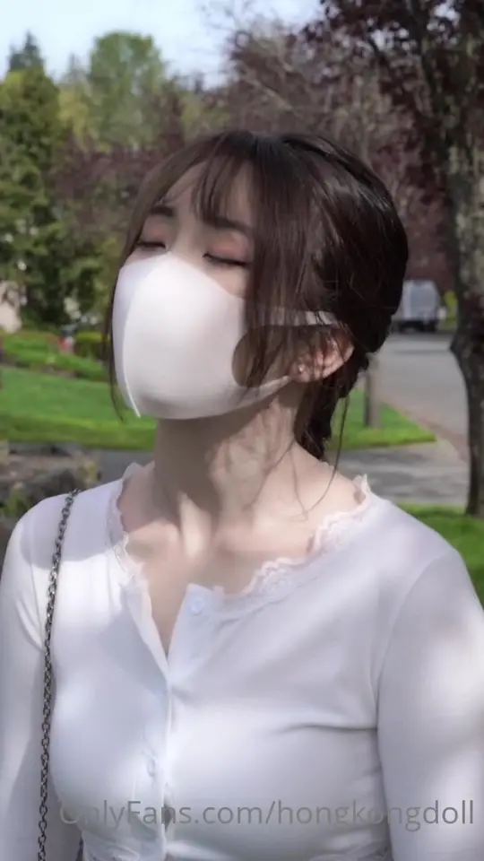 Masked brunette poses on a sunny street