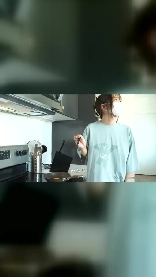 Masked woman fries egg in kitchen
