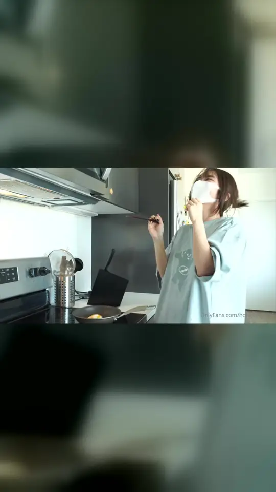 Masked woman fries egg in kitchen